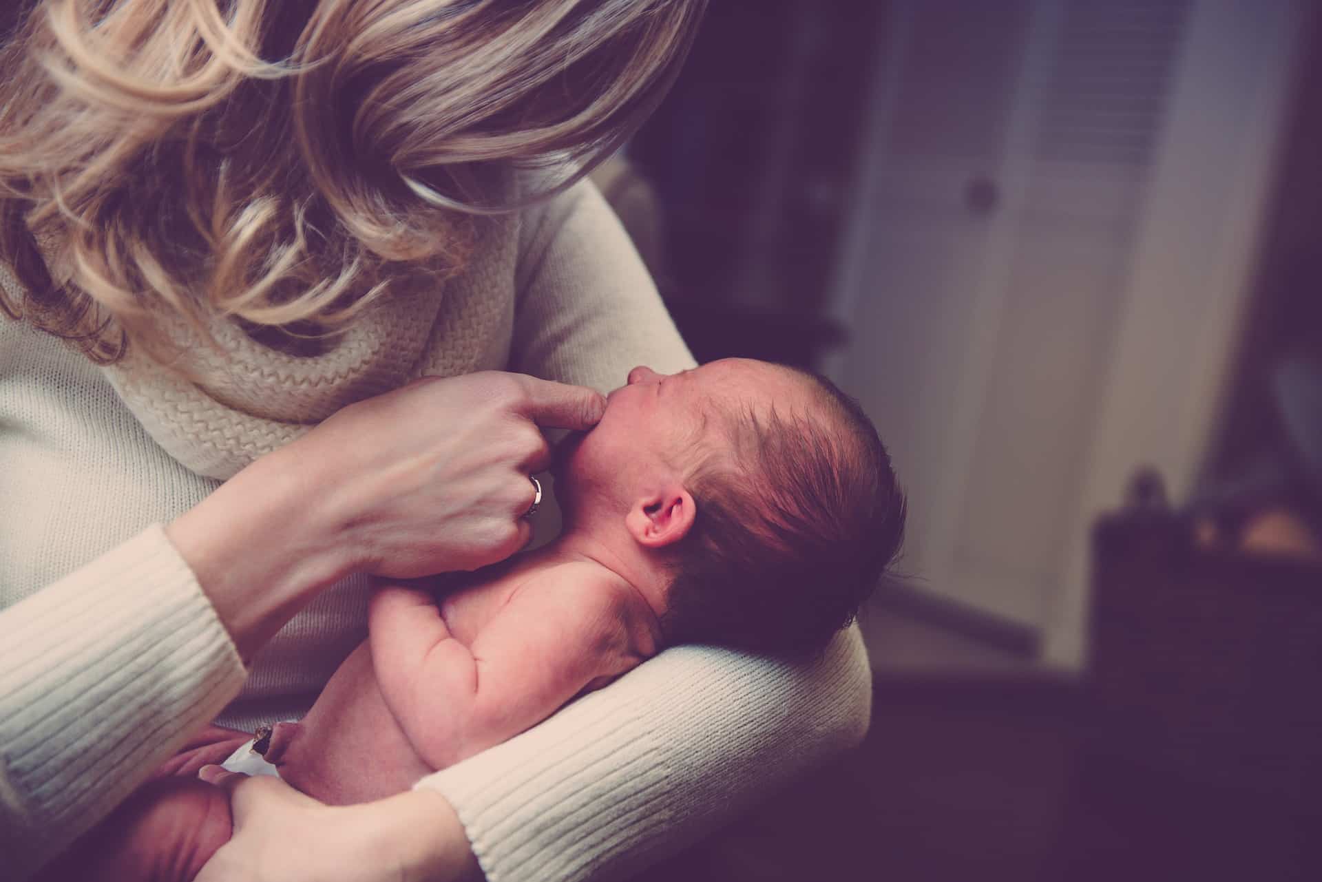 UN ammaman portant un bébé dans une maison