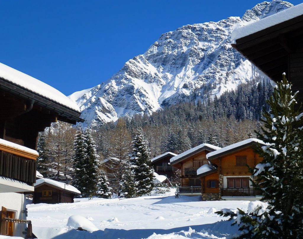 chalets enneigés face à la montagne sous un ciel bleu