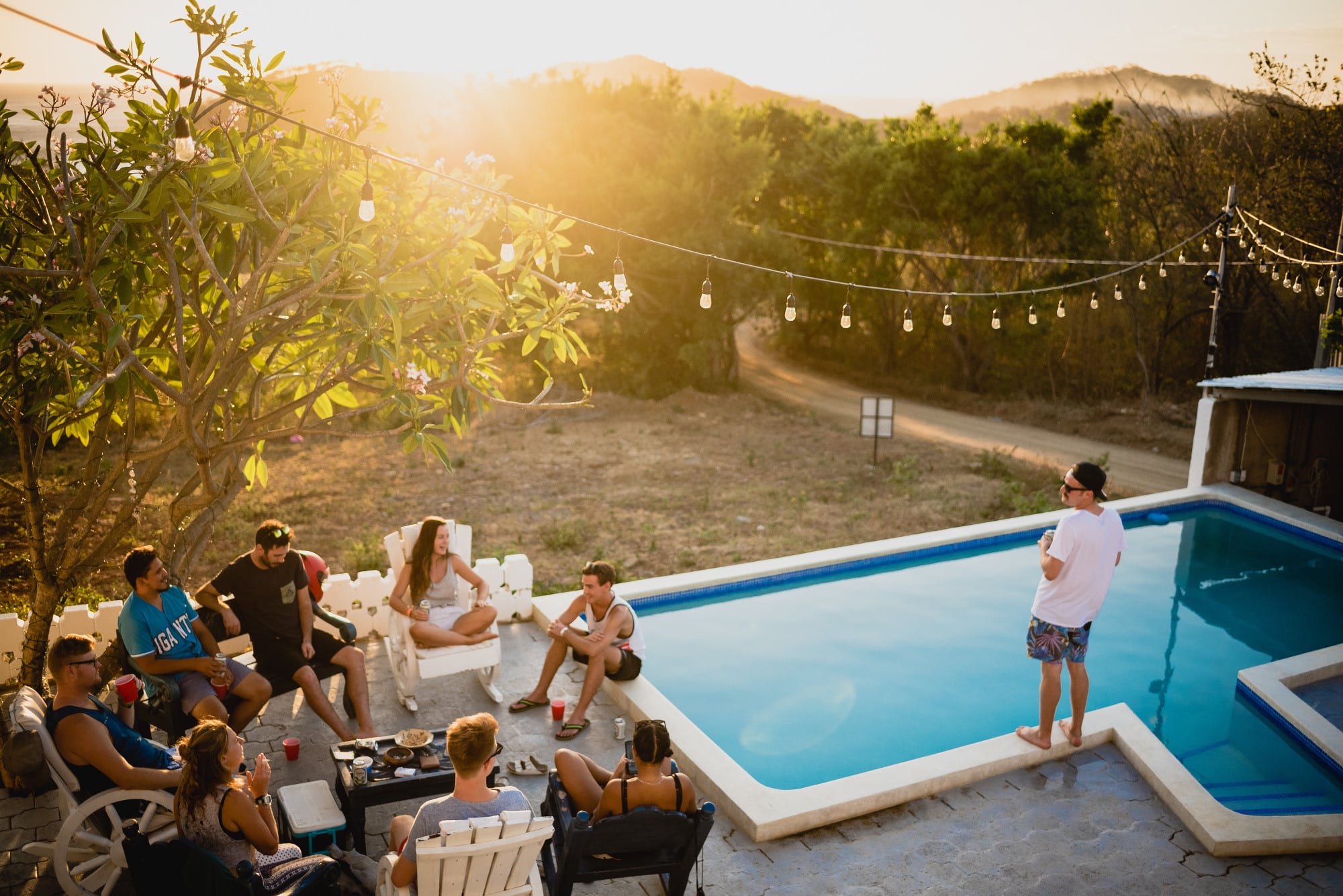 extérieur de maison avec piscine et guirlandes lumineuses avec personnes qui font la fête